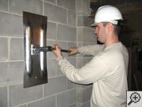 Attempting to straighten a bowed foundation wall by straightening a wall anchor system in a Lewiston home.