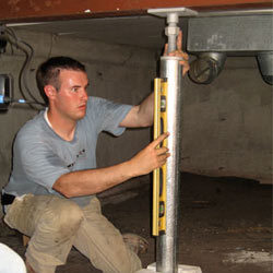 A contractor in Rexburg installing a crawl space jack post.