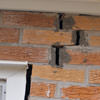 A brick wall displaying stair-step cracks and messy tuckpointing on a Nampa home