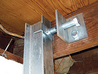 Securing the i-beam system to the top of the floor joist in a foundation wall repair in Lewiston.