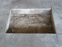 Creating the hole in the garage slab floor during the wall anchor installation in Eagle.