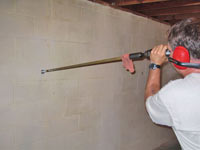 Drilling the hole in the foundation wall for street creep repairs in Kuna