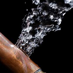A bursting copper pipe in Nampa, with water gushing out.