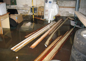 A severely flooding basement in Lewiston, with lumber and personal items floating in a foot of water