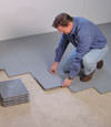 Contractors installing basement subfloor tiles and matting on a concrete basement floor in Coeur D Alene, Idaho